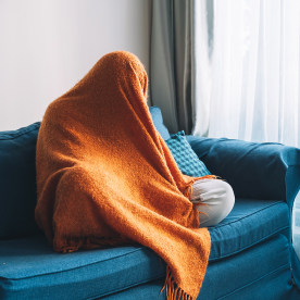 Person on the couch with blanket over head.